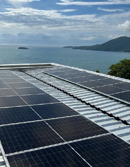Módulos fotovoltaicos em telhado metálico com vista para o mar em Ubatuba